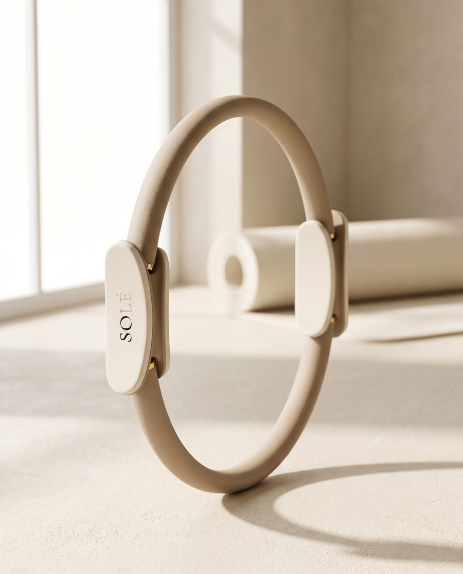 The SOLÉ Sculpt Ring — warm nude foam pilates ring standing upright in soft studio light
