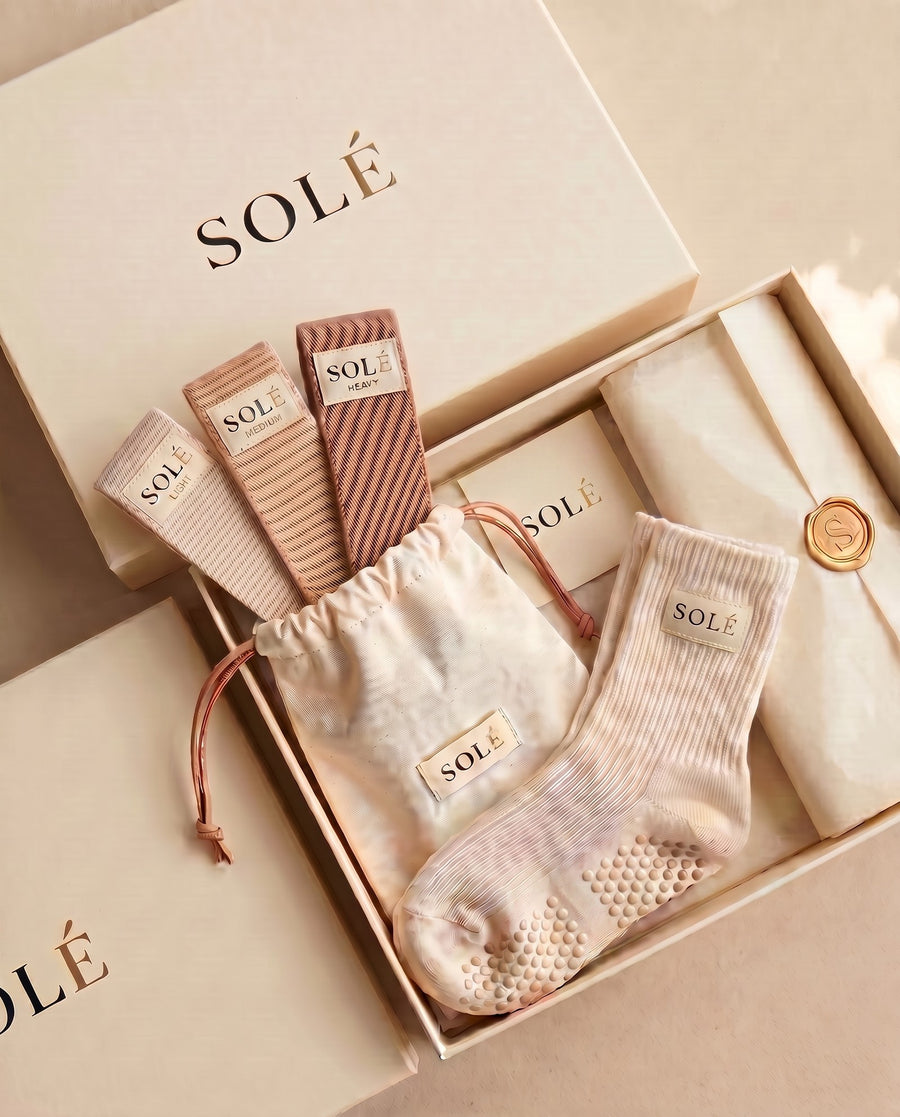 The SOLÉ Starter Kit gift box — cream grip socks paired with the three-band resistance set
