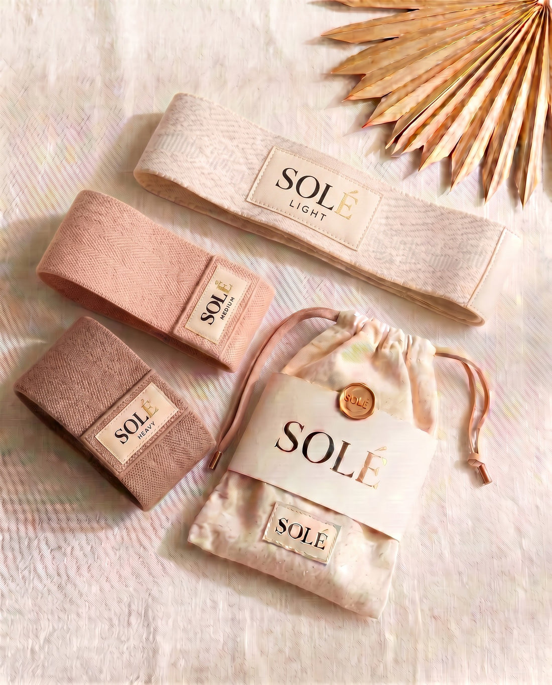 The SOLÉ Band Set — three woven-fabric resistance bands in warm nude tones with a cream cotton drawstring pouch and QR card